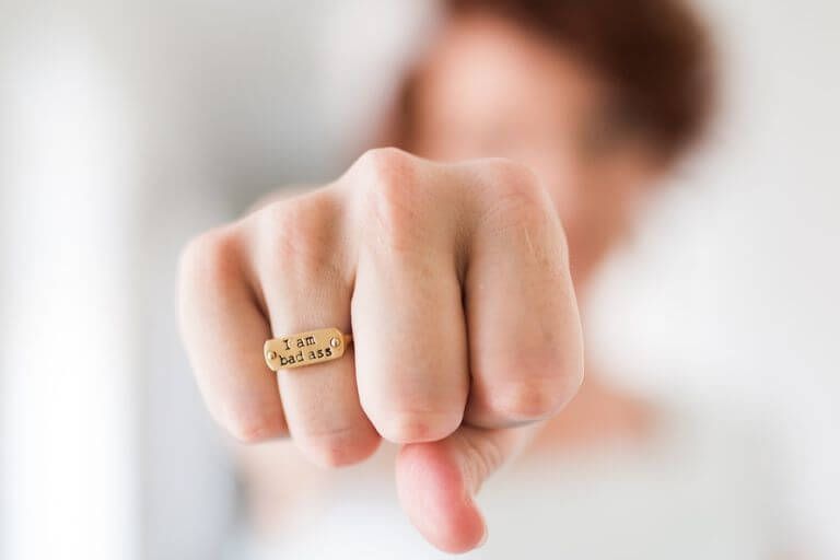Frau streckt die Faust entgegen und trägt einen Ring mit der Aufschrift "I am bad ass".